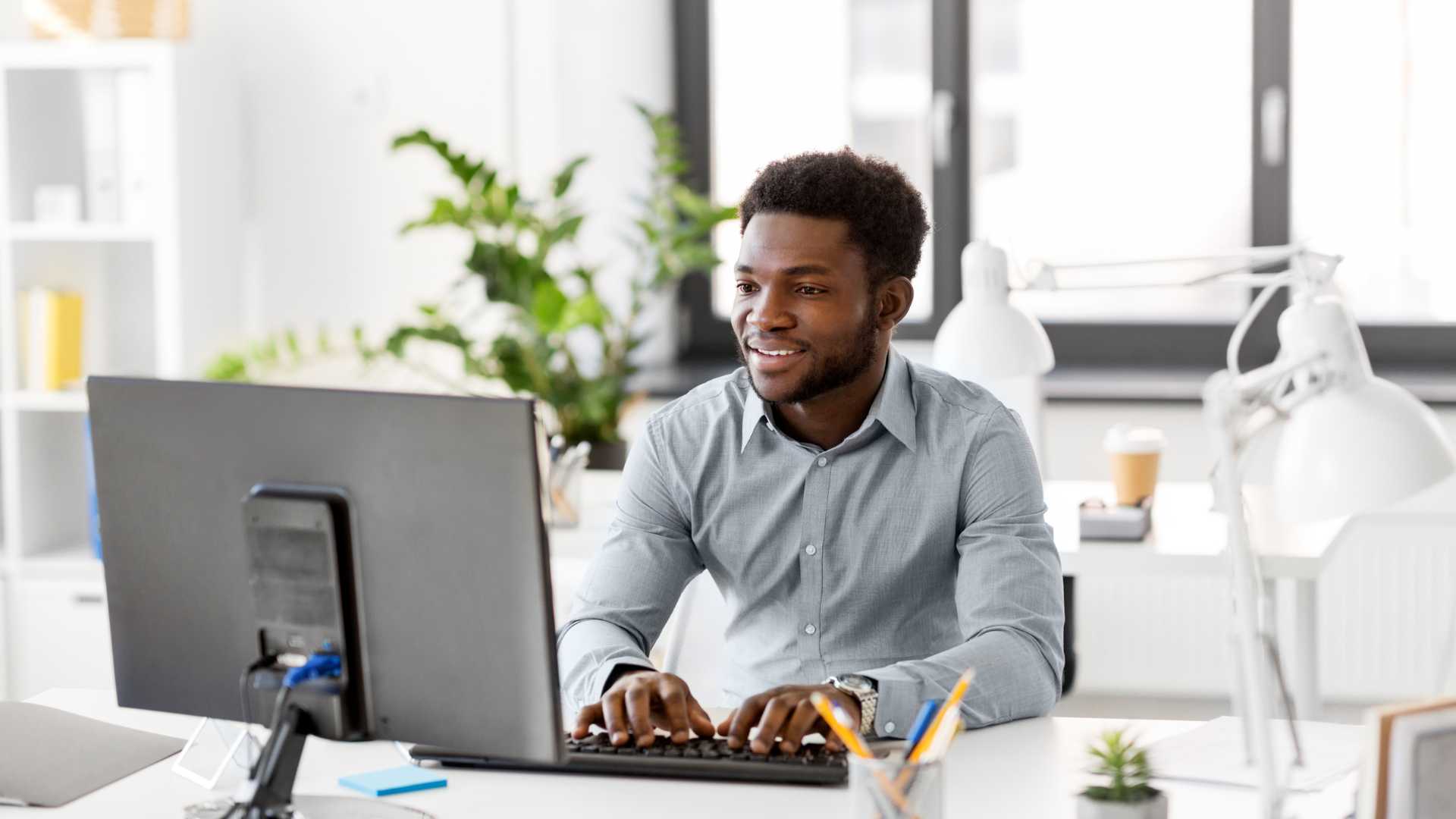 happy young business man typing on computer in office